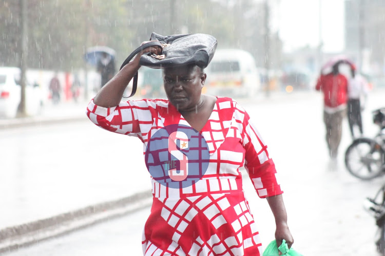 A woman uses her hand bag to protect herself from the rain on March 14, 2023