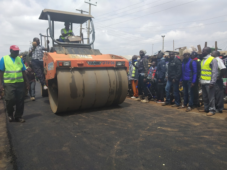 Thika MP Patrick Wainaina (operating the roller) with Makongeni residents during the commissioning of Madaraka market road on Monday