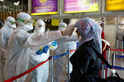 Iraqi medical staff check passengers' temperature, amid coronavirus outbreak, upon their arrival from Iran, at Najaf airport, Iraq March 5, 2020. 