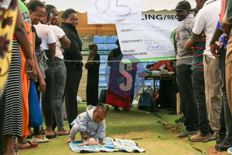 A child plays with her doll as her mother queues to cast her vote at Uwanja wa Mbuzi in Kongowea, Nyali constituency, in Mombasa on August 9, 2022