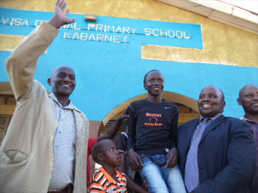 A.I.C Visa Oshwal head teacher Job Kimitei(in tie)-public school raises shoulders high Denis Tarus after scoring 400 marks in just released KCPE results. His father Simon Ruto raises hand to thank God for the remarkable results. PHOTO/JOSEPH KANGOGO