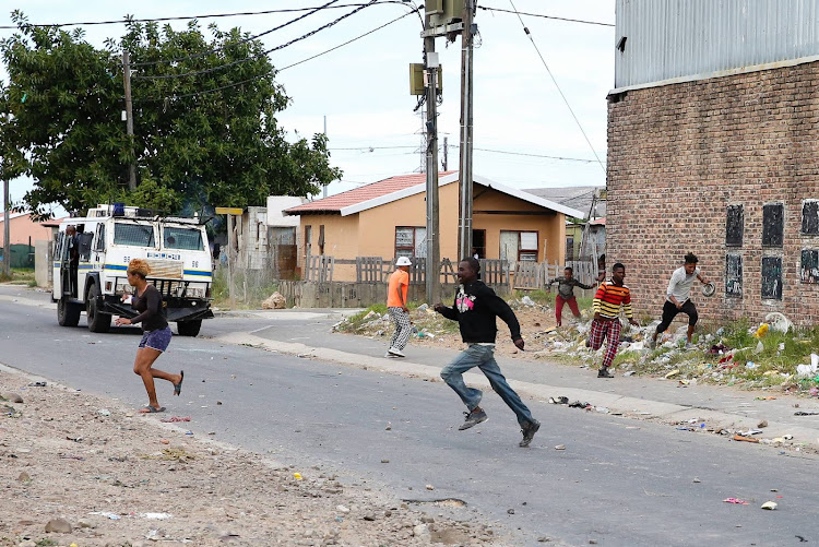 Residents run for cover after police started firing rubber bullets shortly after a shop was looted in Timothy Valley on April 14