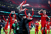 Liverpool manager Juergen Klopp celebrates with the trophy and his players after winning the League Cup final against Chelsea at Wembley in London on Sunday.