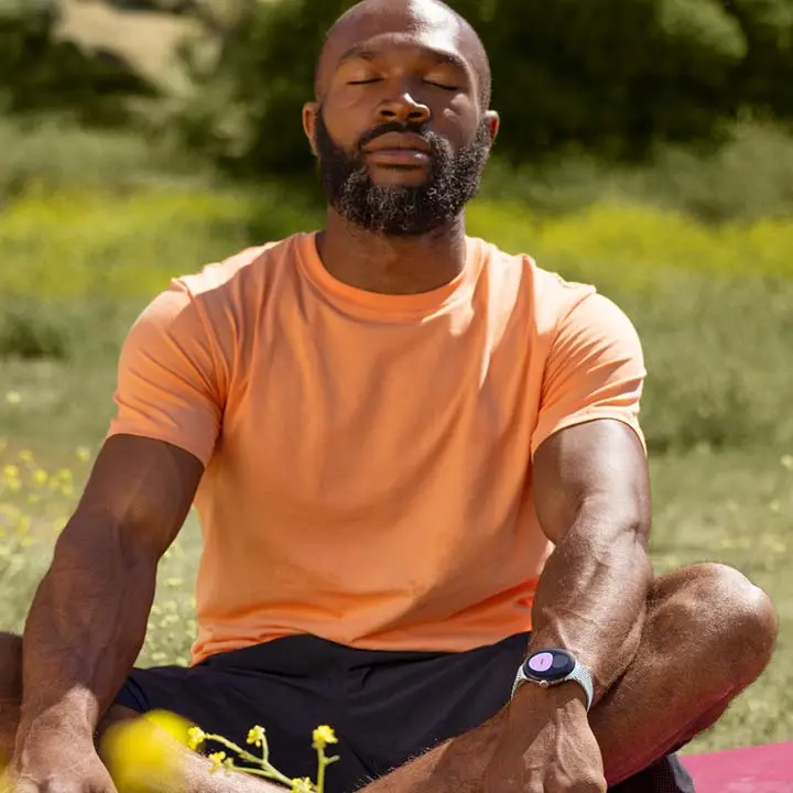A person meditating in a field with Pixel Watch 2