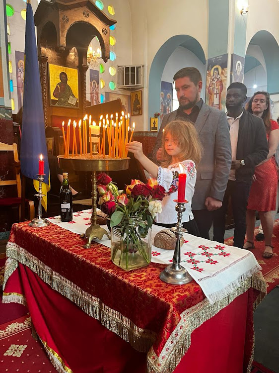 A young girl places a candle in the sandbox during the commemoration service for the victims of the Holodomor genocide at the Orthodox Patriarchal Cathedral of Sts. Cosmas and Damian, on Valley road, Nairobi on November 25, 2023.