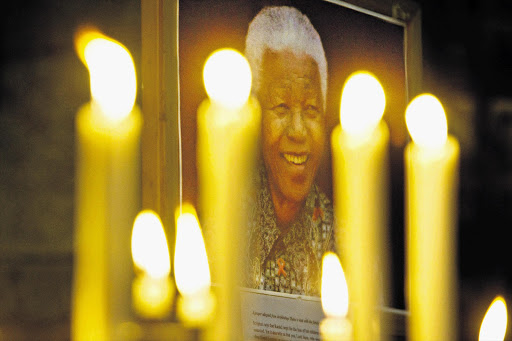 A portrait of Nelson Mandela illuminated by candles at the St George's Cathedral in Cape Town. A section of the church has been set aside for people to come and say a prayer and light a candle for him.