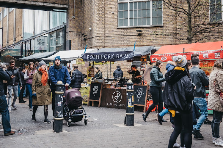 People walking past food stalls on Brick Lane, London. The street is the heart of London's Bangladeshi-Sylheti community and is famous for its market.