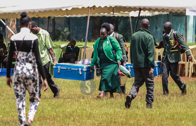 Parents carry a box for a learner during Form one admission at Jamhuri Boys in Nairobi on January 15, 2024.