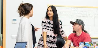 Woman in focus, conversing with people, smiling.