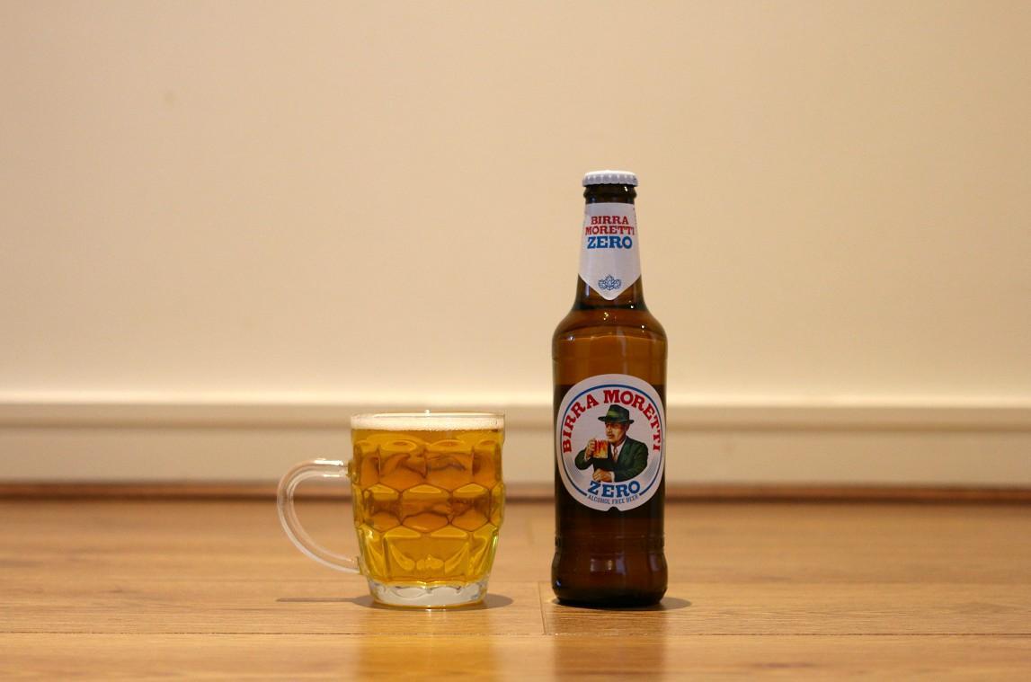 Birra Moretti beer bottle sitting on a desk beside a beer mug