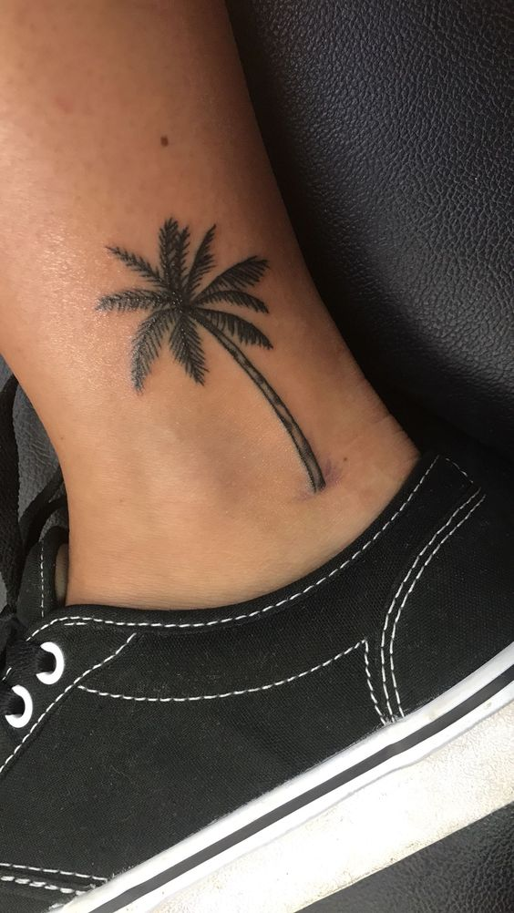 Another view of the palm tree tattoo on the ankle of a guy