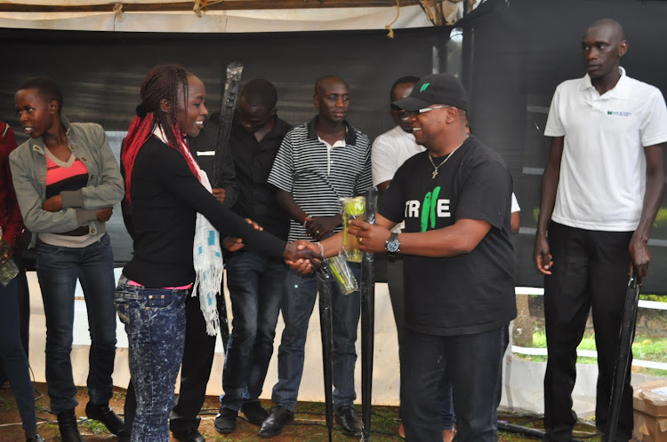 Bank of Africa's Head of Marketing Jimmi Wanjohi (R) presents a gift to elite marathon runners during a viewing party for the 2017 World Marathon Majors in Kapsabet.