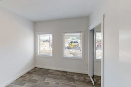 Bedroom with patterned carpet, white walls, two outlets, and two windows