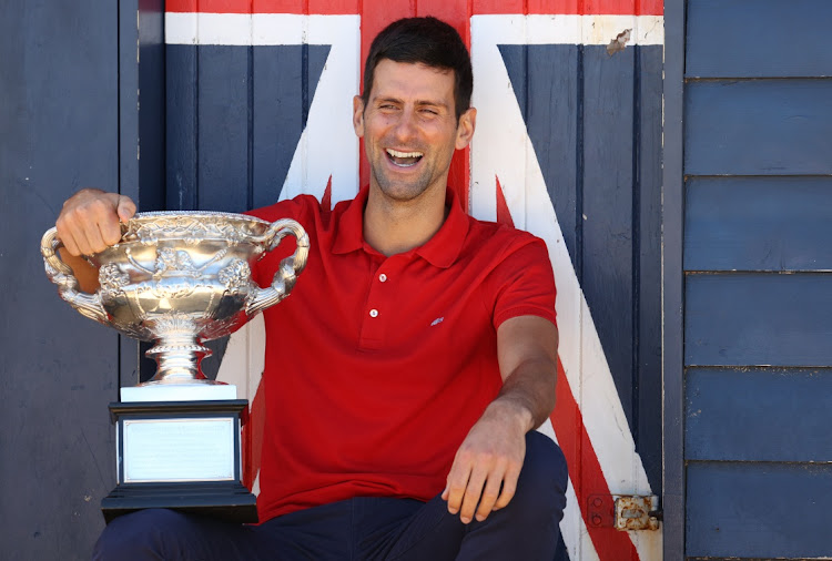 Serbia's Novak Djokovic poses with the Australian Open trophy during a photo shoot at Brighton Beach, Melbourne on February 22, 2021