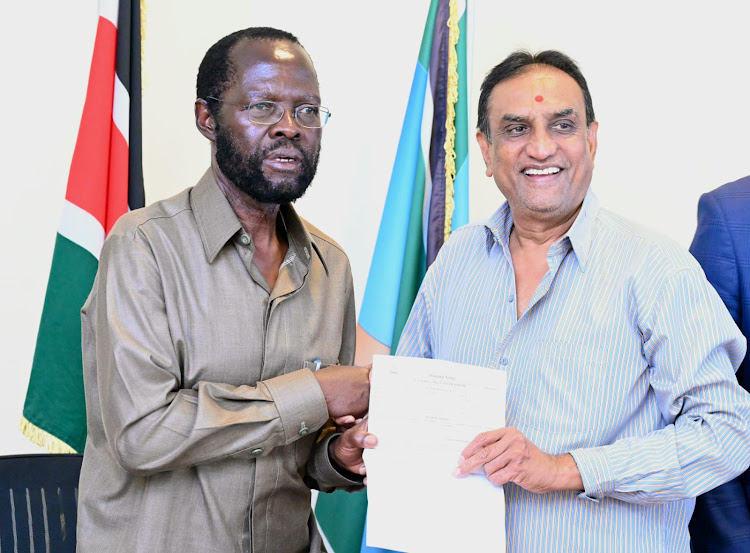 Kisumu Governor Anyang Nyong'o receives a title deed of the reclaimed piece of land being surrendered by businessman Naresh Patel at City hall on Thursday.