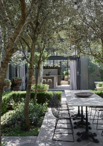 The dark exterior walls of this suburban house work wonderfully to emphasise the lush greenery of the garden, while the formality created by the box hedges and olive trees gives it a timeless quality.