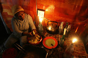 Sinethemba Khunou, who works at Vukusebenze takeaways at Nompumelelo township in East London, uses a gas stove for frying chips as candles provide the light during load shedding.