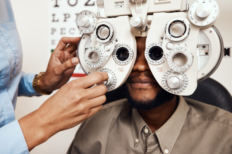 An optometrist examining her patients' eyes with an optical refractor.