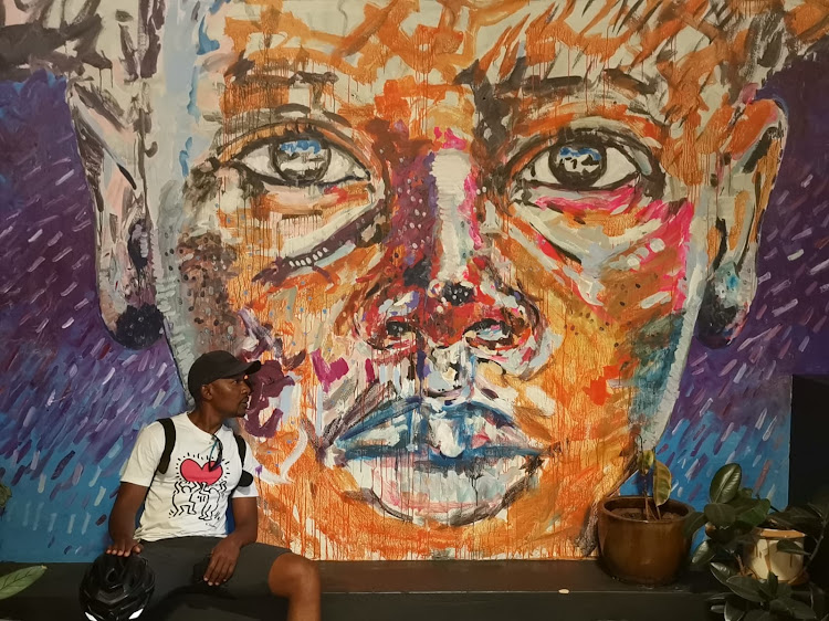 Kennedy Tembo in front of a piece by local and internationally renowned artist Nelson Markamo.