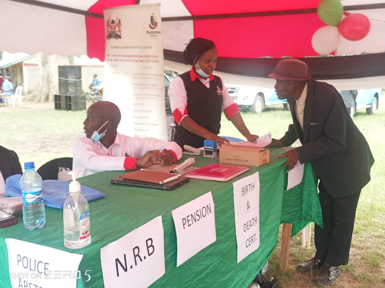 An elderly man consults Huduma staff during a Huduma Mashinani outreach in Kakamega.