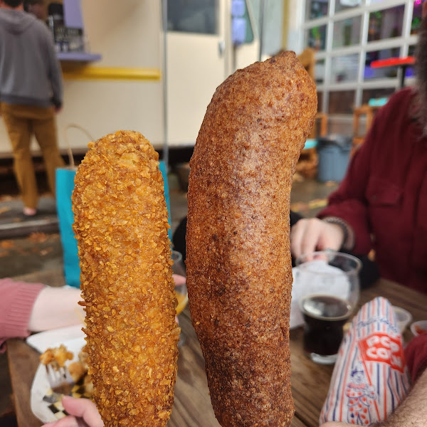 Vegan corn dog left, giant bratwurst right, both chip covered