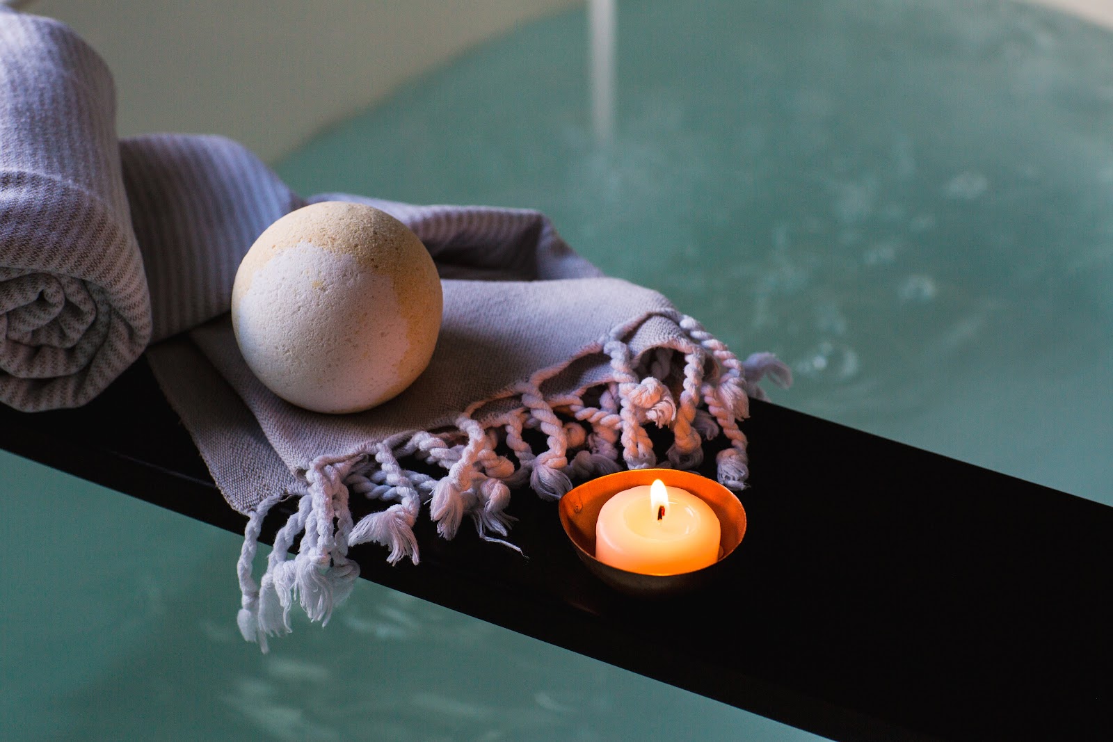 candle and bath bomb next to bath tub