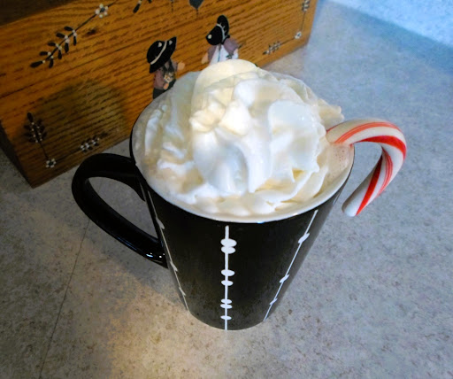 Photo of pepper flavored coffee, topped with whipped cream and served with a peppermint candy cane.