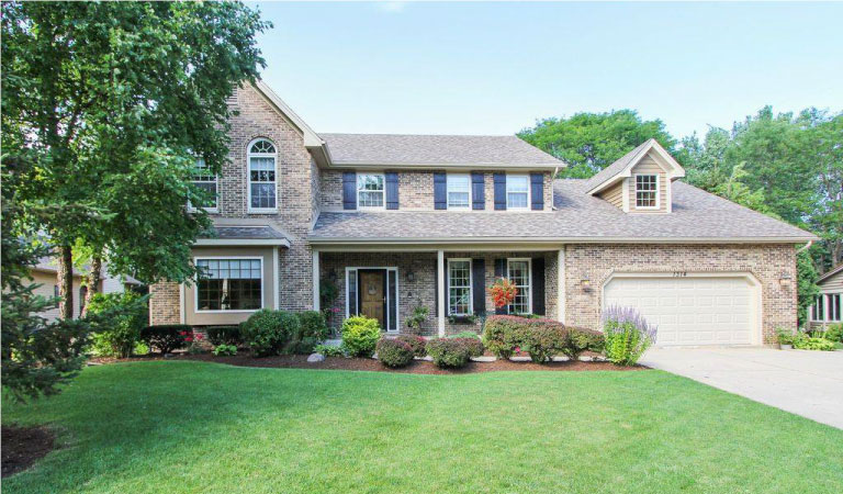 A two-story brick home in Libertyville, Illinois, with a lovely manicured lawn.
