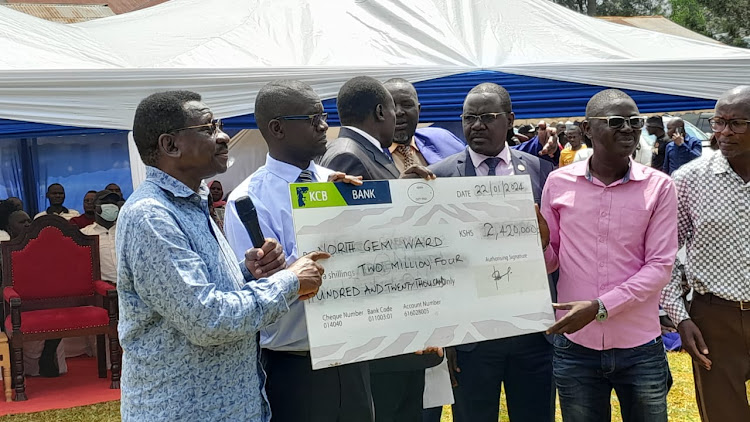 Siaya governor James Orengo presents a dummy cheque to schools in Gem constituency on Monday. Sh 110.6 million has been allocated by the county government for bursaries and scholarships to 18,081 needy students from the county