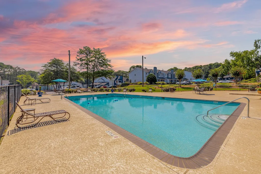 Community swimming pool with lounge chairs and seating areas with umbrellas at dusk