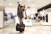 A customer carries her purchases in a branded shopping bag after shopping at a Truworths International Ltd. fashion store in Sandton, South Africa, on Tuesday, Aug. 12, 2014.