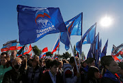 People hold flags of Russia's ruling United Russia party. 