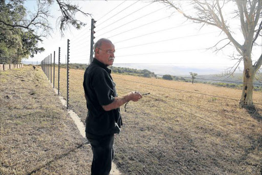 LUCKY TO BE ALIVE: Igoda area farmer Basil Peinke at the electric fence where robbers dropped some coins while trying to scale the perimeter prior to an attack Picture: MARK ANDREWS