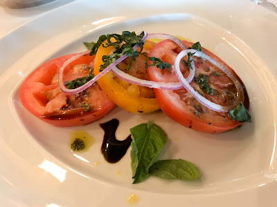 A beefsteak tomato appetizer with basil, red onion and pesto, served at Pinnacle Grill on Oosterdam. 