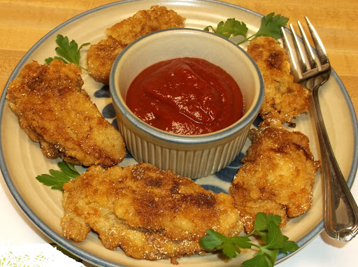 Pan-fried oysters plated with cocktail sauce.
