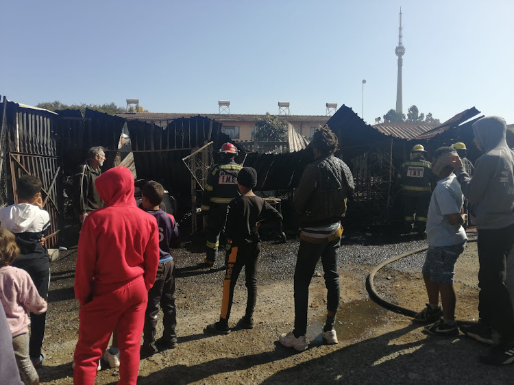 Residents watch firefighters extinguish the blaze. Three vehicles were destroyed, including a newly purchased car the owner had not driven.