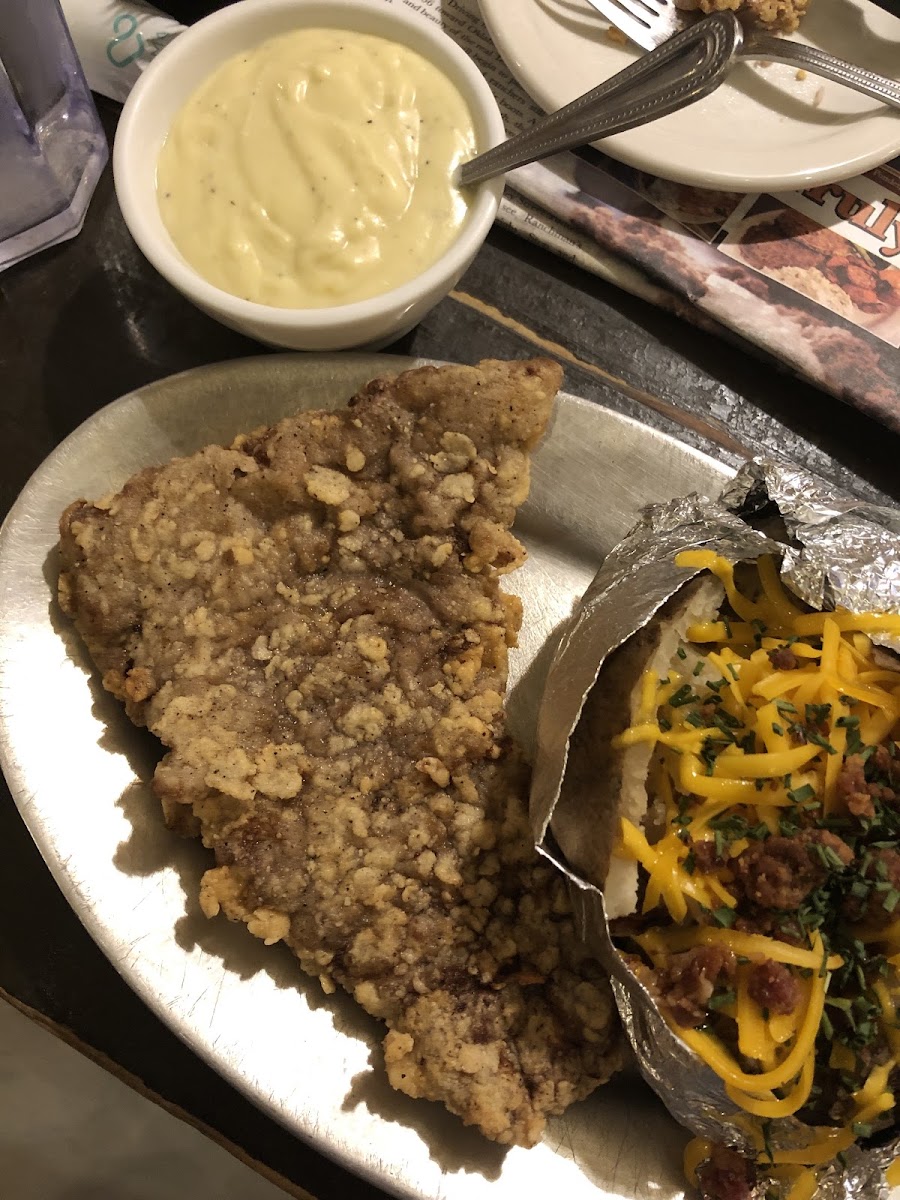 Chicken fried steak with homemade gravy and a baked potato.