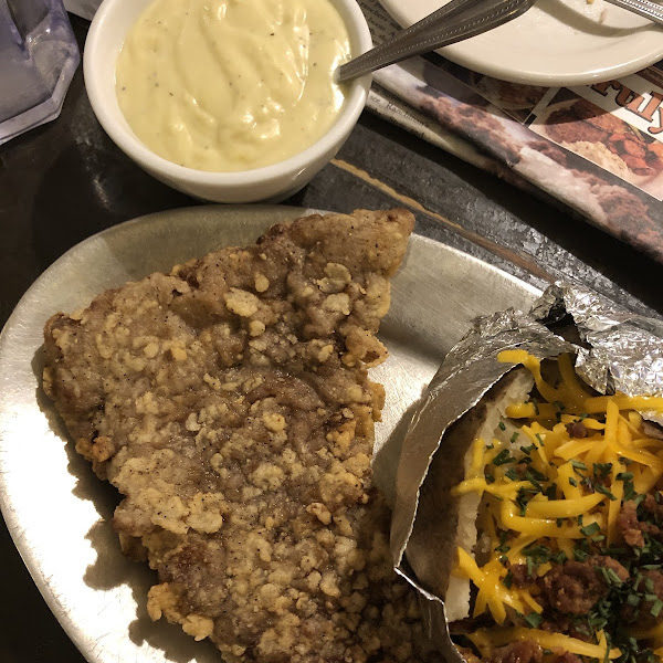 Chicken fried steak with homemade gravy and a baked potato.