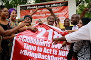 Members of the #BringBackOurGirls (#BBOG) campaign react on the presentation of a banner which shows 