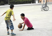 Qin Xulei plays basketball with a friend in Yichuan county, China. Qin, 13, lost his legs in a car accident when he was three. He hopes to represent China in basketball in the Paralympic Games