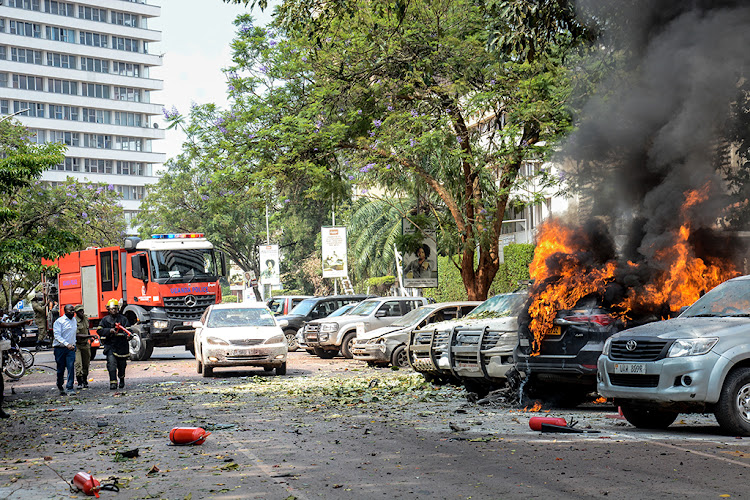 First responders assess carnage and extinguish car fires caused by a suicide bomb explosion near the entrance to Parliament building in Kampala, Uganda, on November 16.