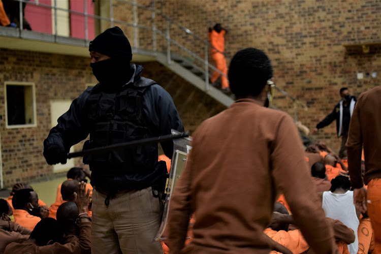 A correctional services officer orders inmates to leave their cells and sit in the quad with their hands above their heads during a raid at Qalakabusha Correctional Centre on Tuesday.