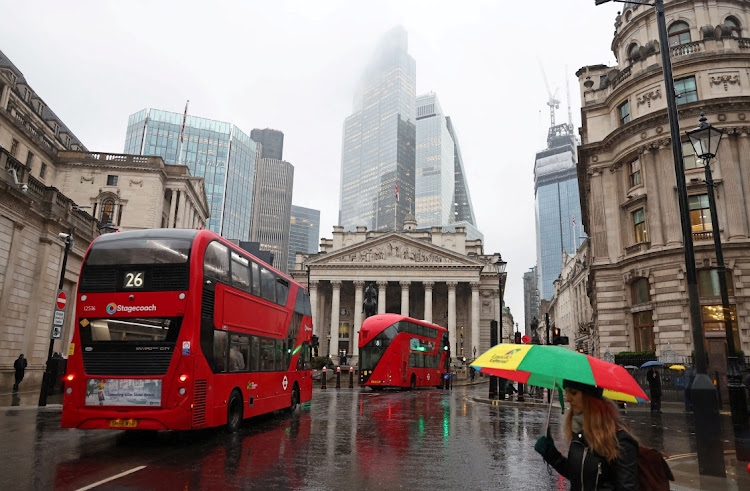 Commuters walk as buses go past during the morning rush hour near the Bank of England in London. Picture: TOBY MELVILLE