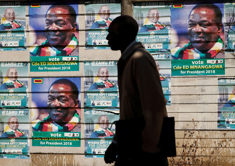 A man walks past election posters of President Emmerson Mnangagwa's ruling Zanu-PF party in Harare, Zimbabwe, July 26, 2018.