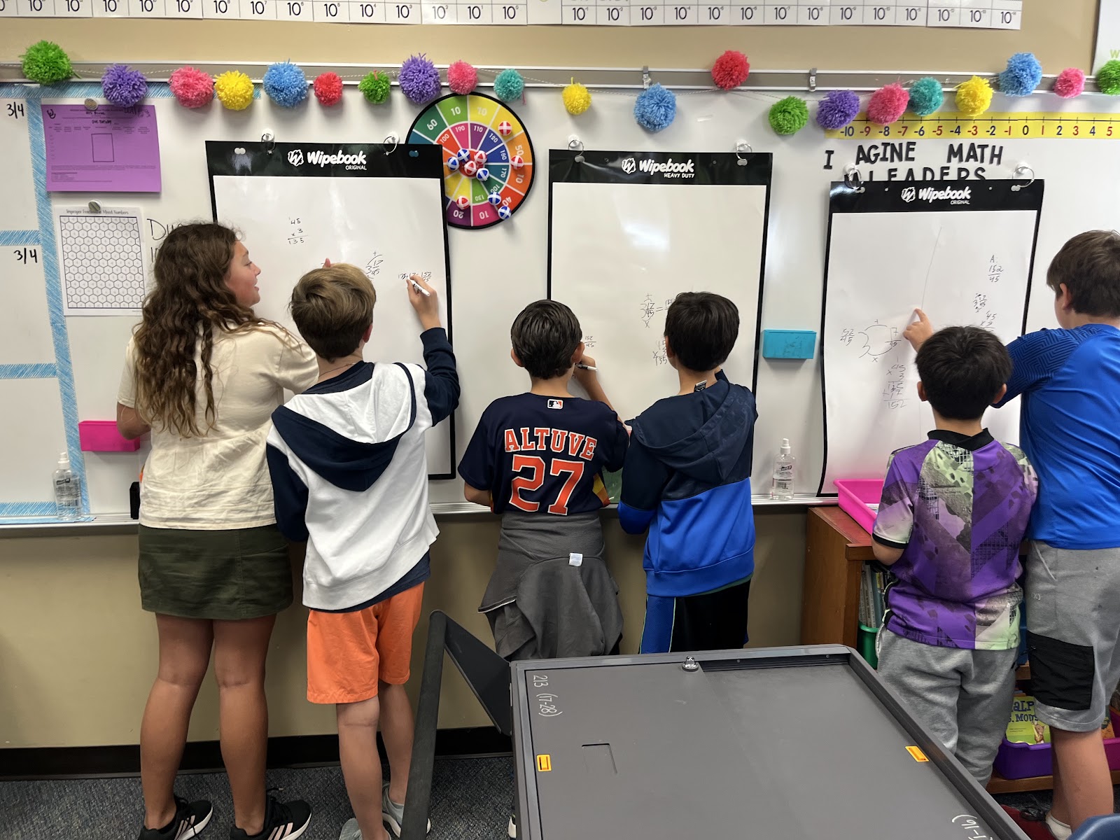 3 groups of students work in pairs on separate flipcharts solving math problems