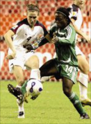 BATTLE: US forward Heather O'Reilly, left, and Nigeria's Faith Ikidi fight for the ball in their Group B match. Pic. Eugene Hoshiko. 18/09/07. © AP.