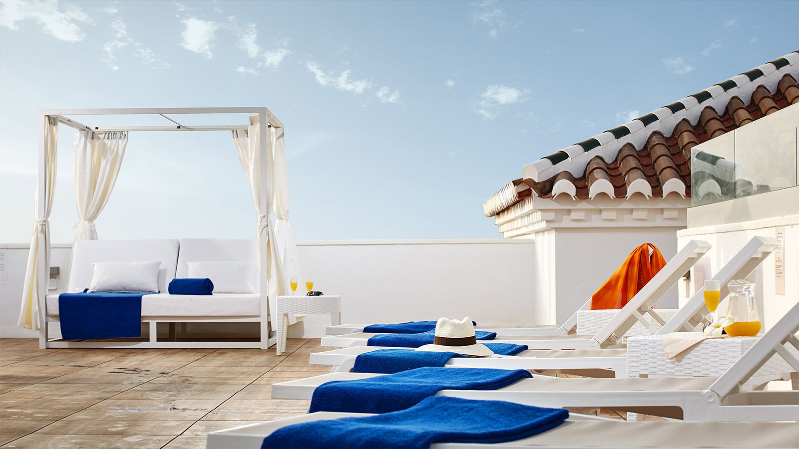 white lounge chairs with blue towels and a canopy bed