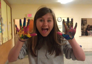 member of youth group holding up paint-smeared hands