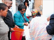 GIVING HAND: Marjorie manganye hands out food hampers to the elderly while staff members and sponsors look on appreciatively. Pic. Lindi Obose. © Sowetan.