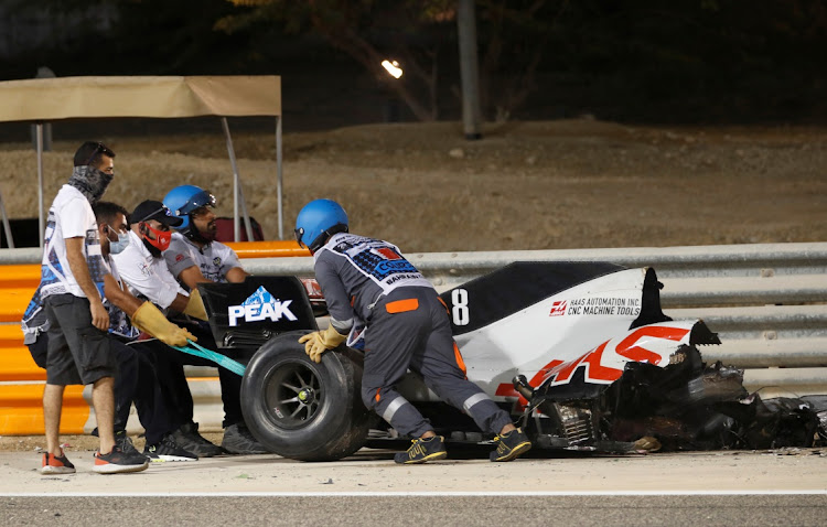 Stewards clear the car of Haas' Romain Grosjean from the track during the F1 Bahrain Grand Prix at Bahrain International Circuit, Sakhir on November 29, 2020